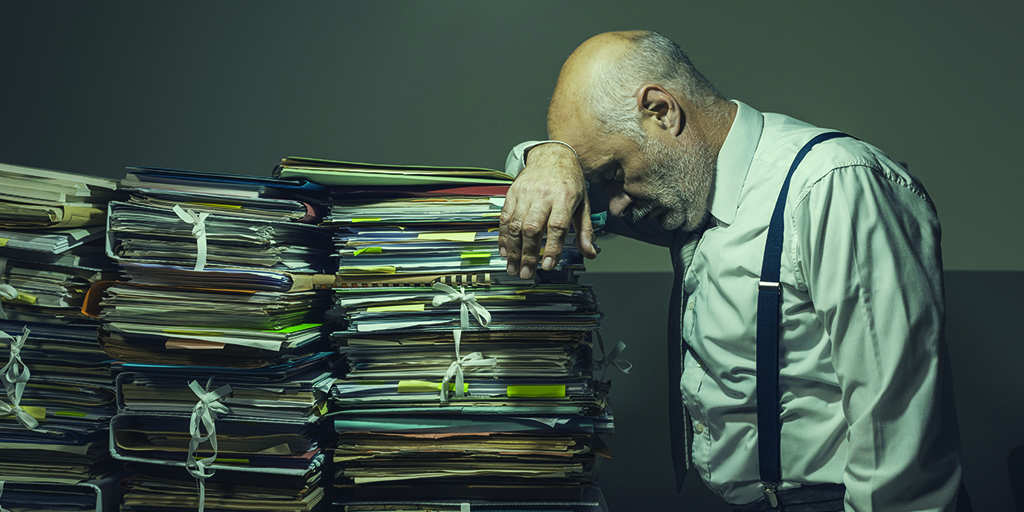 An image of a stressed entrepreneur leaning on stacks of files