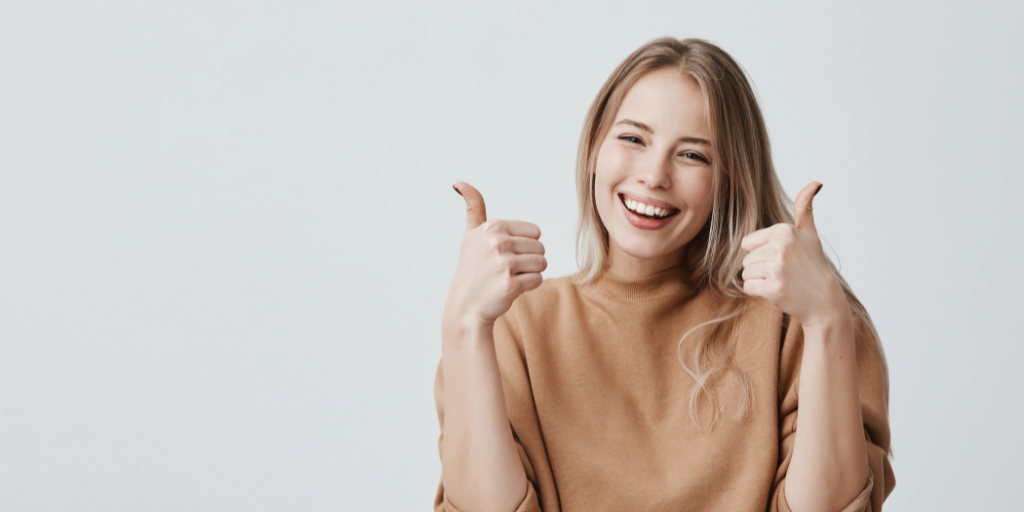A smiling bookkeeper with both thumbs up in the air, indicating a good job